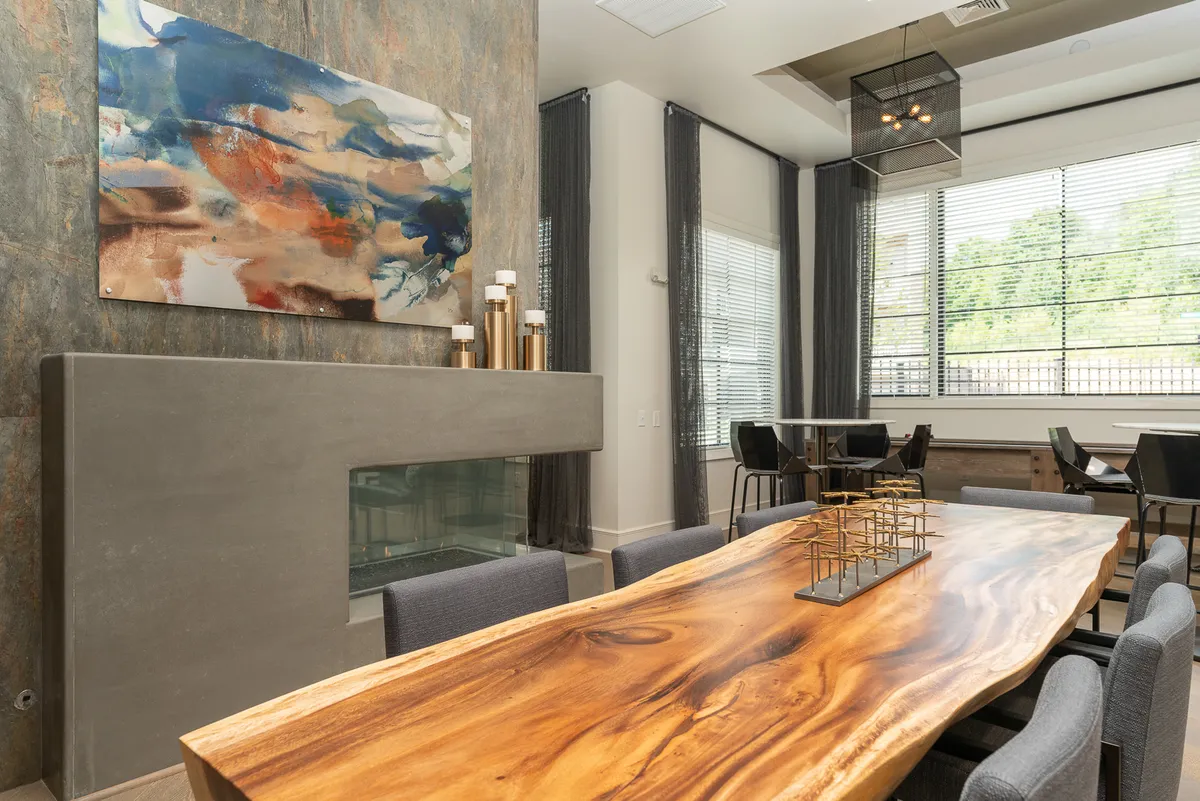 A modern dining area featuring a large wooden table, a contemporary art piece on the wall, and a minimalist fireplace. The space is welcoming and stylish, perfect for hosting gatherings or enjoying everyday meals in a refined setting.