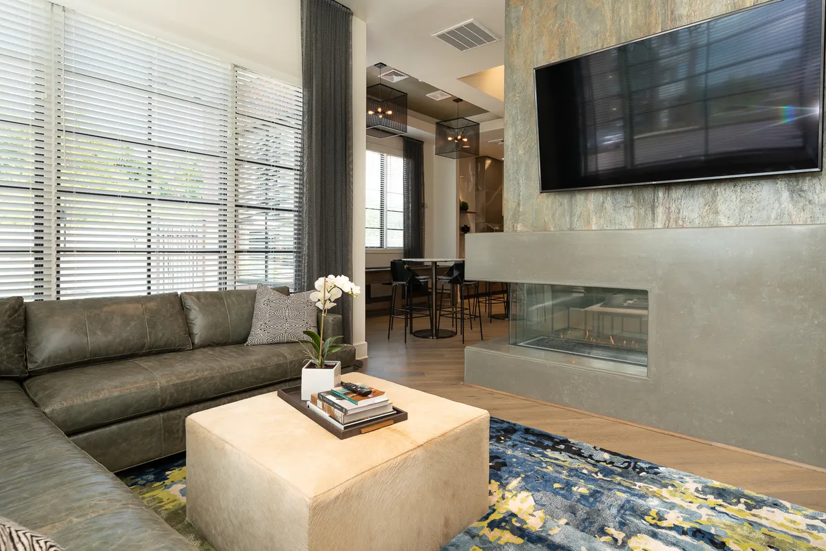 A contemporary living room with a large sectional sofa, coffee table, television, and decorative plant. Natural light streams in from a nearby window, highlighting the inviting and comfortable atmosphere ideal for unwinding after a day out.